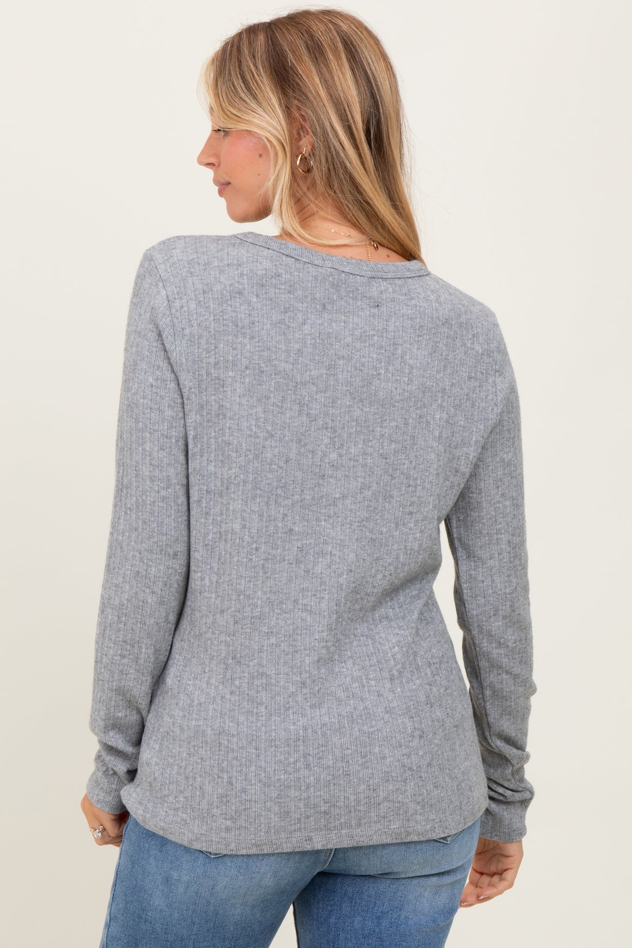 woman wearing a gray ribbed long sleeve top, viewed from the back, paired with light blue jeans