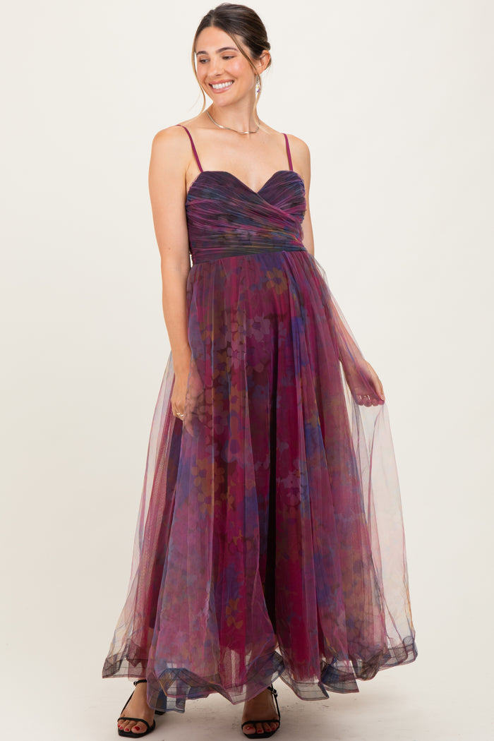 woman wearing a purple floral maternity dress with a flowy skirt and spaghetti straps, showcasing her baby bump
