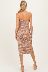 woman wearing a brown and beige ruched maternity dress with spaghetti straps, showing a fitted silhouette from the back