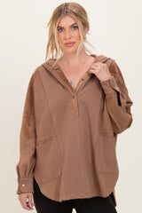 woman wearing a brown oversized hoodie with a button placket and side pockets, styled with black leggings