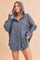 woman wearing a dark blue oversized hoodie with a front pocket and hood, styled with denim shorts