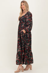 woman wearing a dark floral maxi dress with long sleeves and pockets, styled with beige block heel shoes