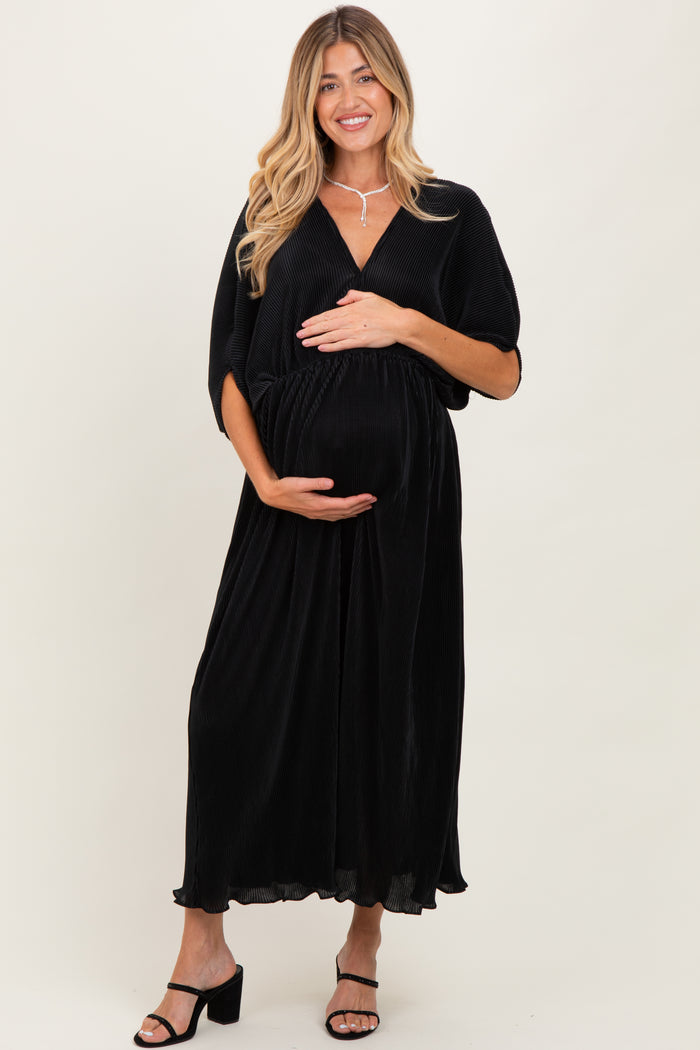 woman wearing a black ribbed maternity maxi dress and holding her baby bump