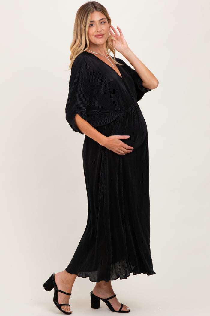 woman wearing a black maternity dress with a cinched waist and v-neck, holding her baby bump