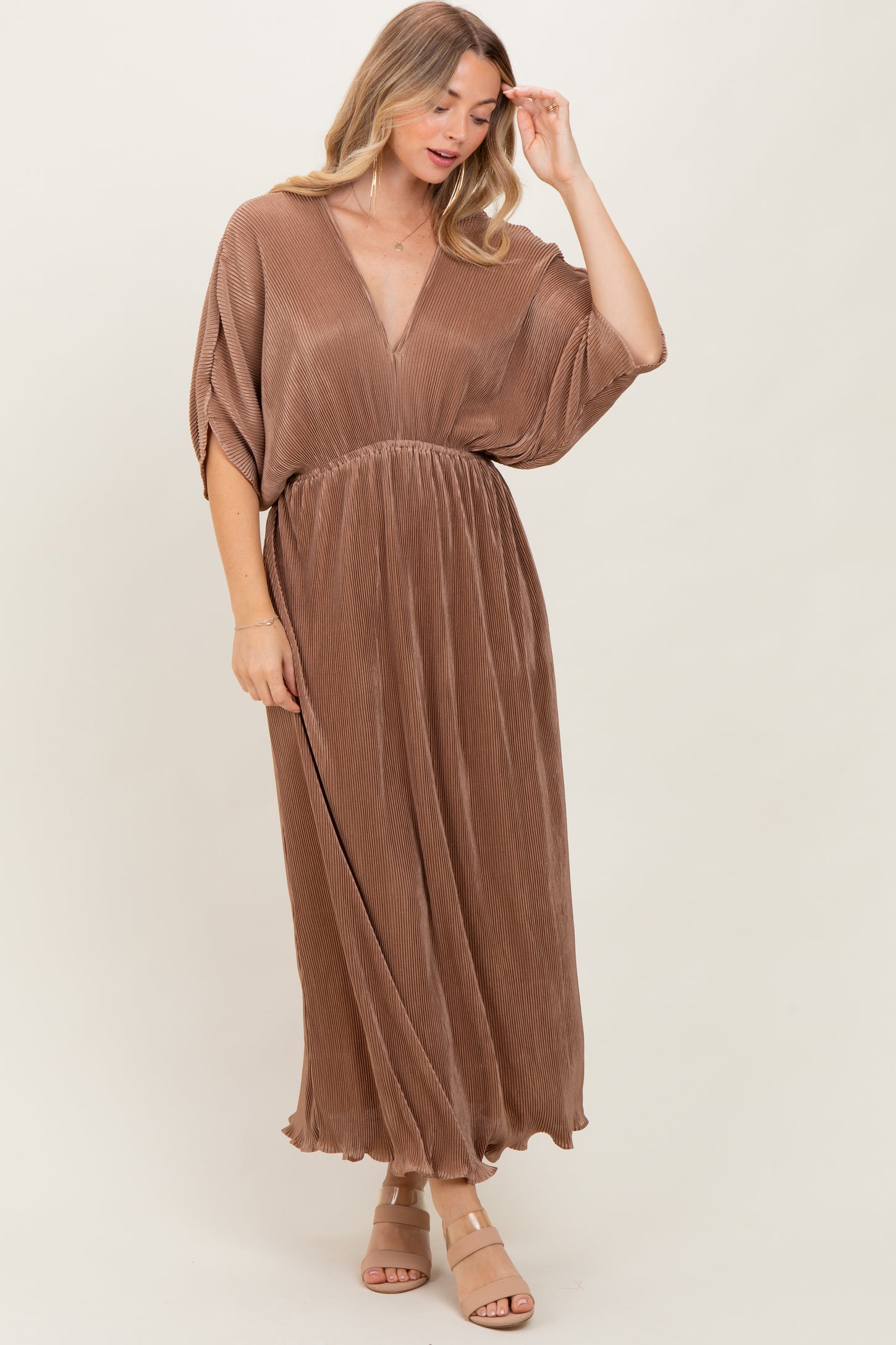 woman wearing a brown pleated maxi dress with a deep v-neck and flowing sleeves