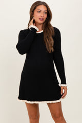 woman wearing a black ribbed maternity dress with cream frill details and long sleeves, showcasing her baby bump