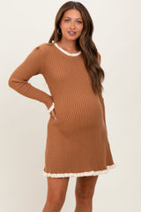 woman wearing a rust ribbed maternity dress with cream ruffle trim and a visible baby bump