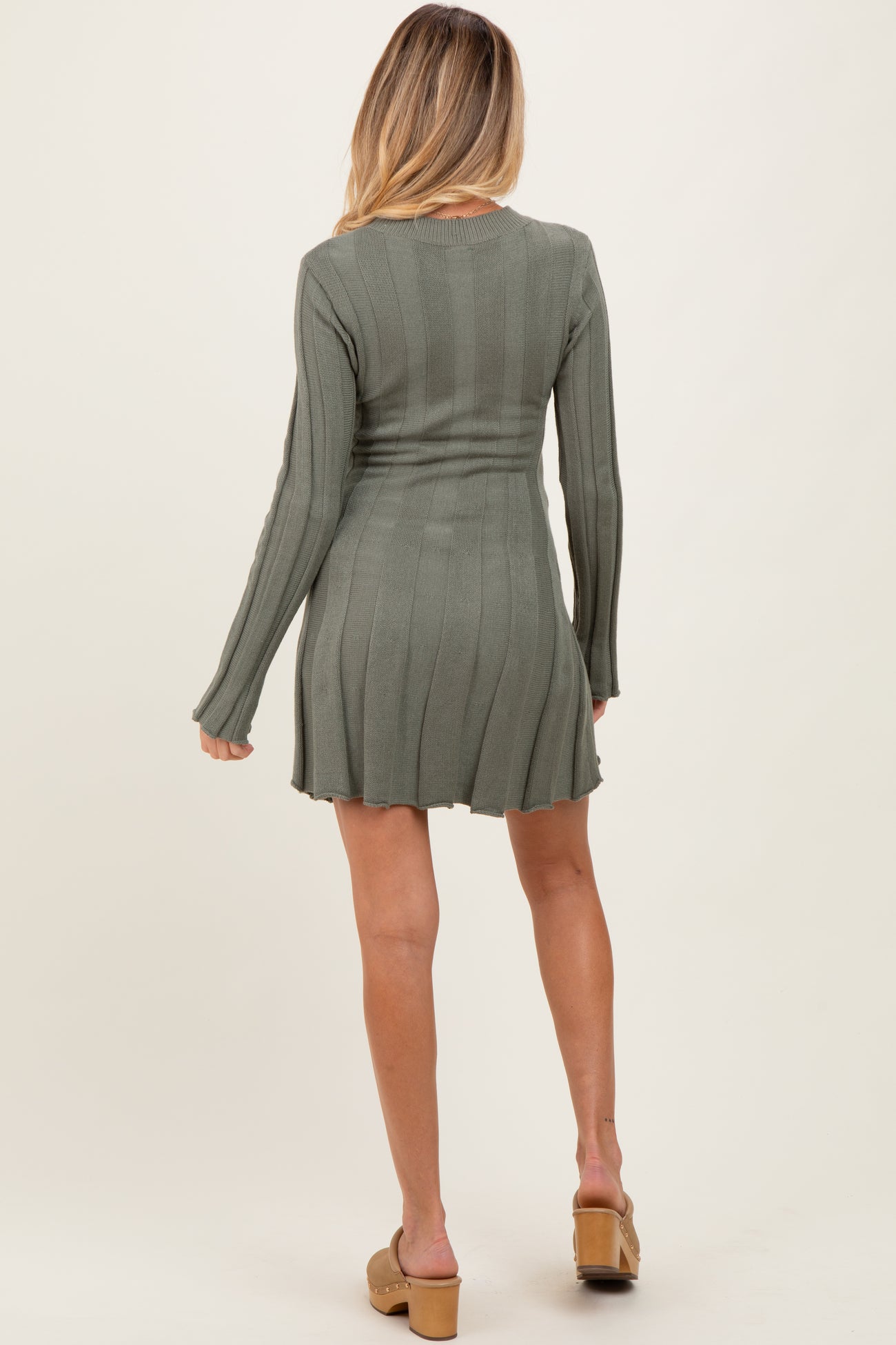 woman wearing a long sleeve olive green ribbed maternity dress with a fitted waist and flared skirt