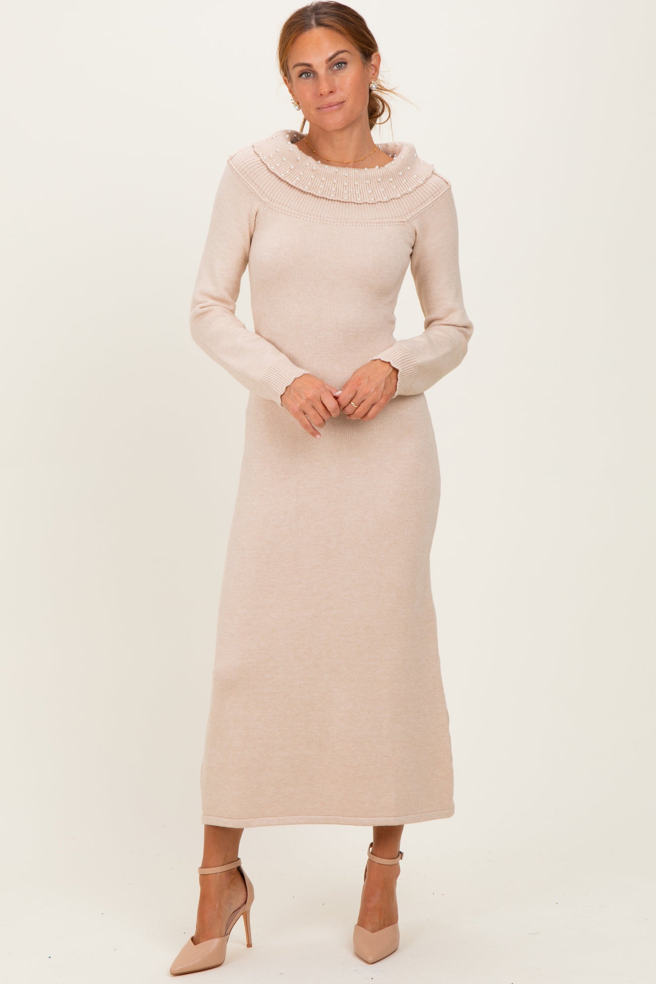 woman wearing a light beige long sleeve sweater dress with a high cowl neck and a fitted silhouette