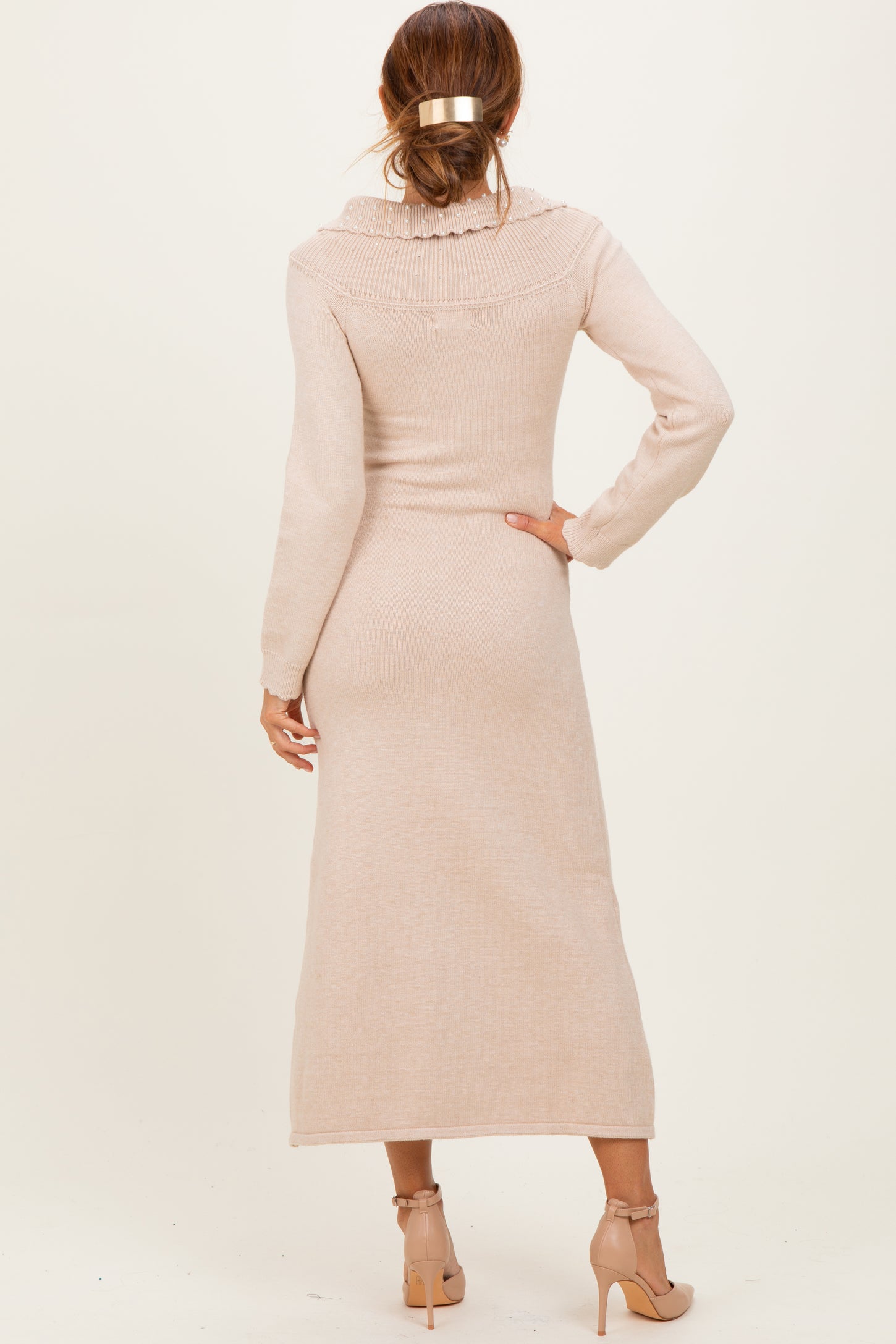 woman wearing a light beige long sleeve ribbed knit maxi dress with a high collar and back tie detail