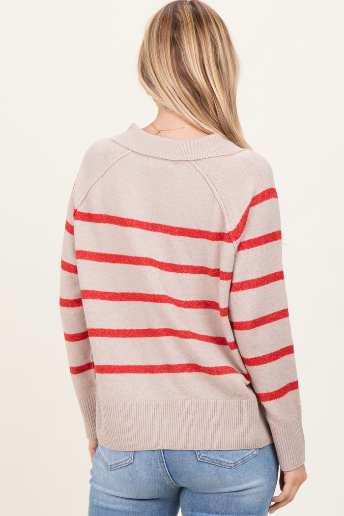 woman wearing a beige sweater with red stripes, shown from the back, paired with blue jeans