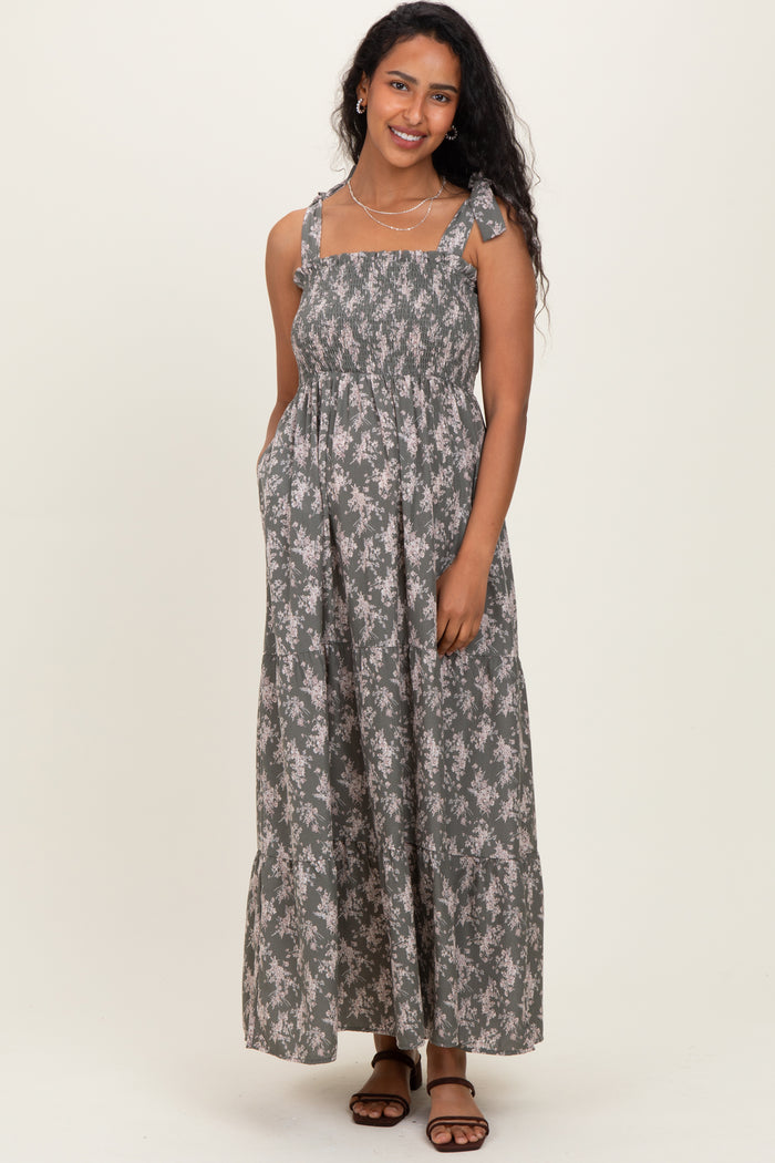 woman wearing a floral patterned gray maternity maxi dress with adjustable straps and pockets