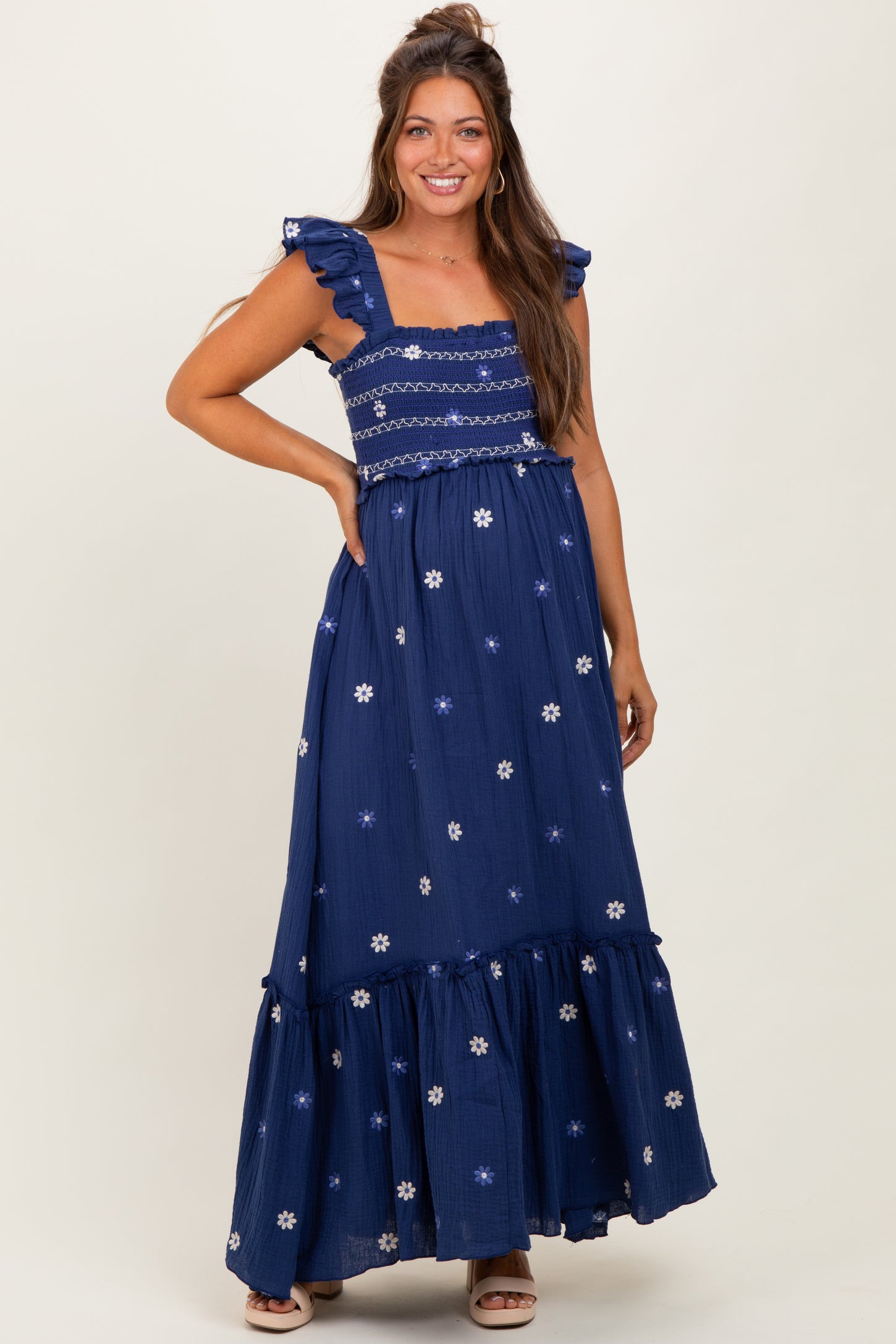 woman wearing a navy blue maternity maxi dress with ruffled straps and floral embroidery