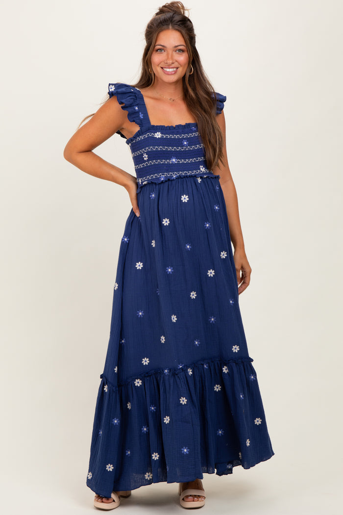 woman wearing a navy blue maternity maxi dress with ruffled straps and floral embroidery