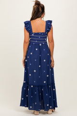 woman wearing a navy blue maternity maxi dress with ruffle sleeves and floral embroidery, showing off her baby bump