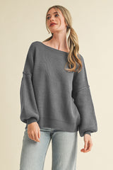 woman wearing a gray ribbed oversized sweater with balloon sleeves and off-the-shoulder neckline, paired with light blue jeans