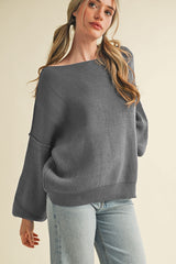 woman wearing a gray off-the-shoulder sweater with long sleeves and light blue jeans