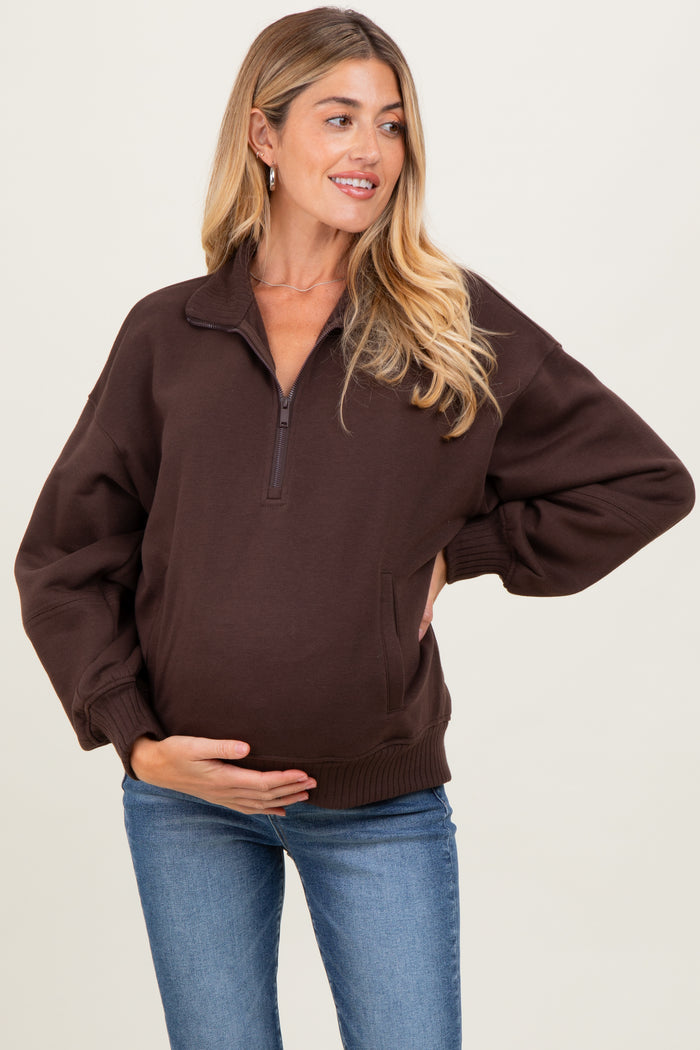 woman wearing a dark brown maternity pullover sweatshirt, showing her baby bump and styled with relaxed fit and quarter zip