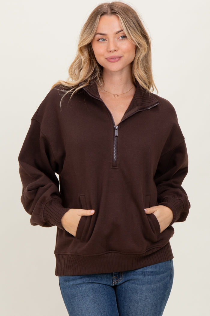 woman wearing a brown half-zip pullover sweatshirt with side pockets and a relaxed fit