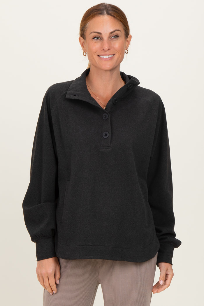 woman wearing a black pullover sweatshirt with a collar and button details, smiling at the camera