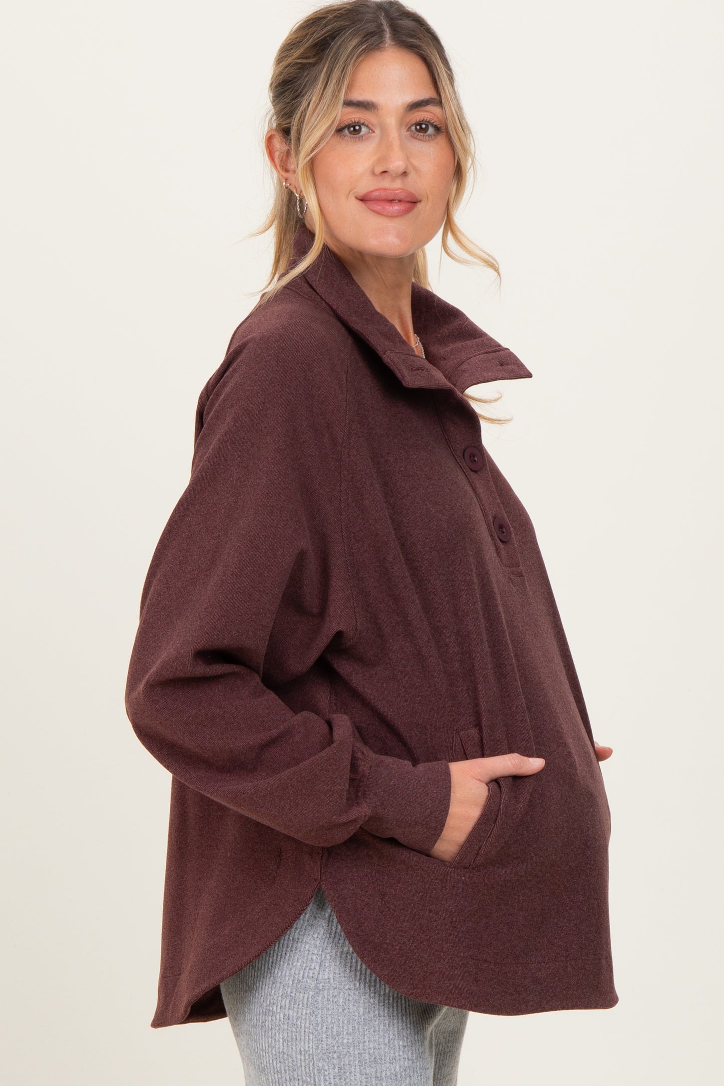 woman wearing a burgundy long sleeve maternity top with a collar and buttons, showing her baby bump