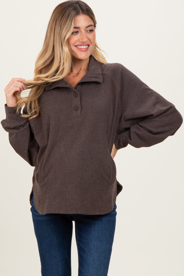 woman wearing a brown fleece maternity pullover with a collar and button details, showing a baby bump