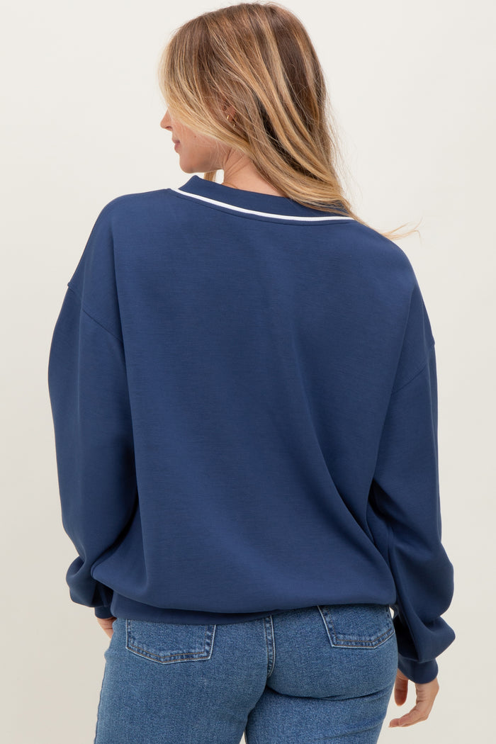 woman wearing a navy blue oversized sweatshirt with a white collar detail, view from the back