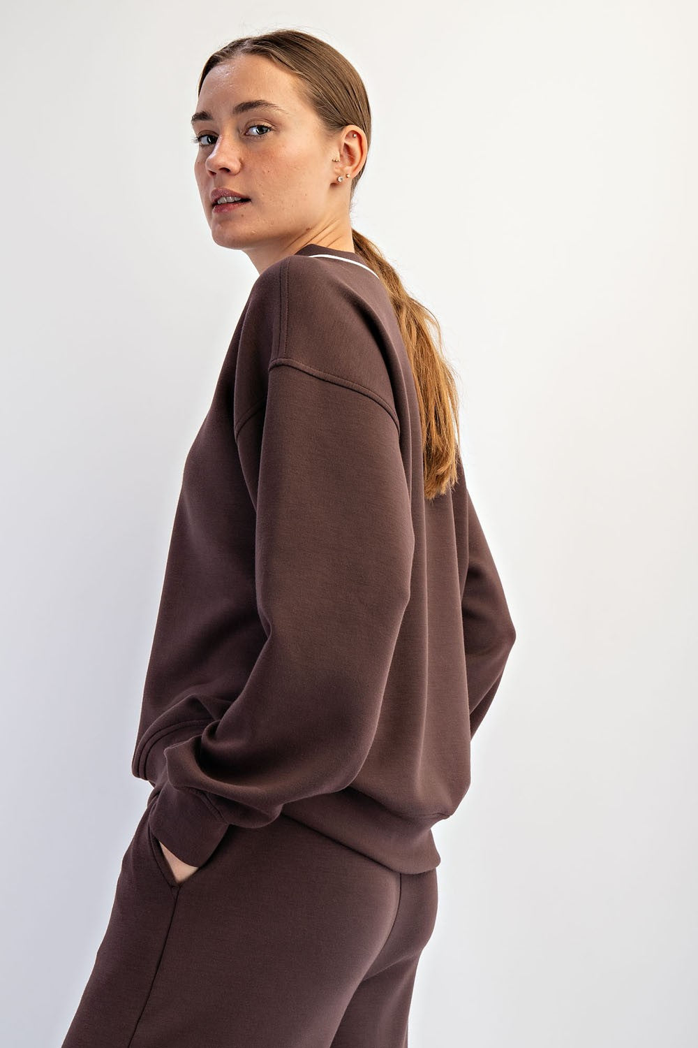 woman wearing a dark brown oversized sweatshirt with dropped shoulders and minimalistic design