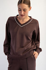woman wearing a brown v-neck sweatshirt with white detailing and relaxed fit, styled with matching pants