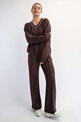 woman wearing a brown v-neck sweatshirt and matching wide-leg pants, styled with white sneakers