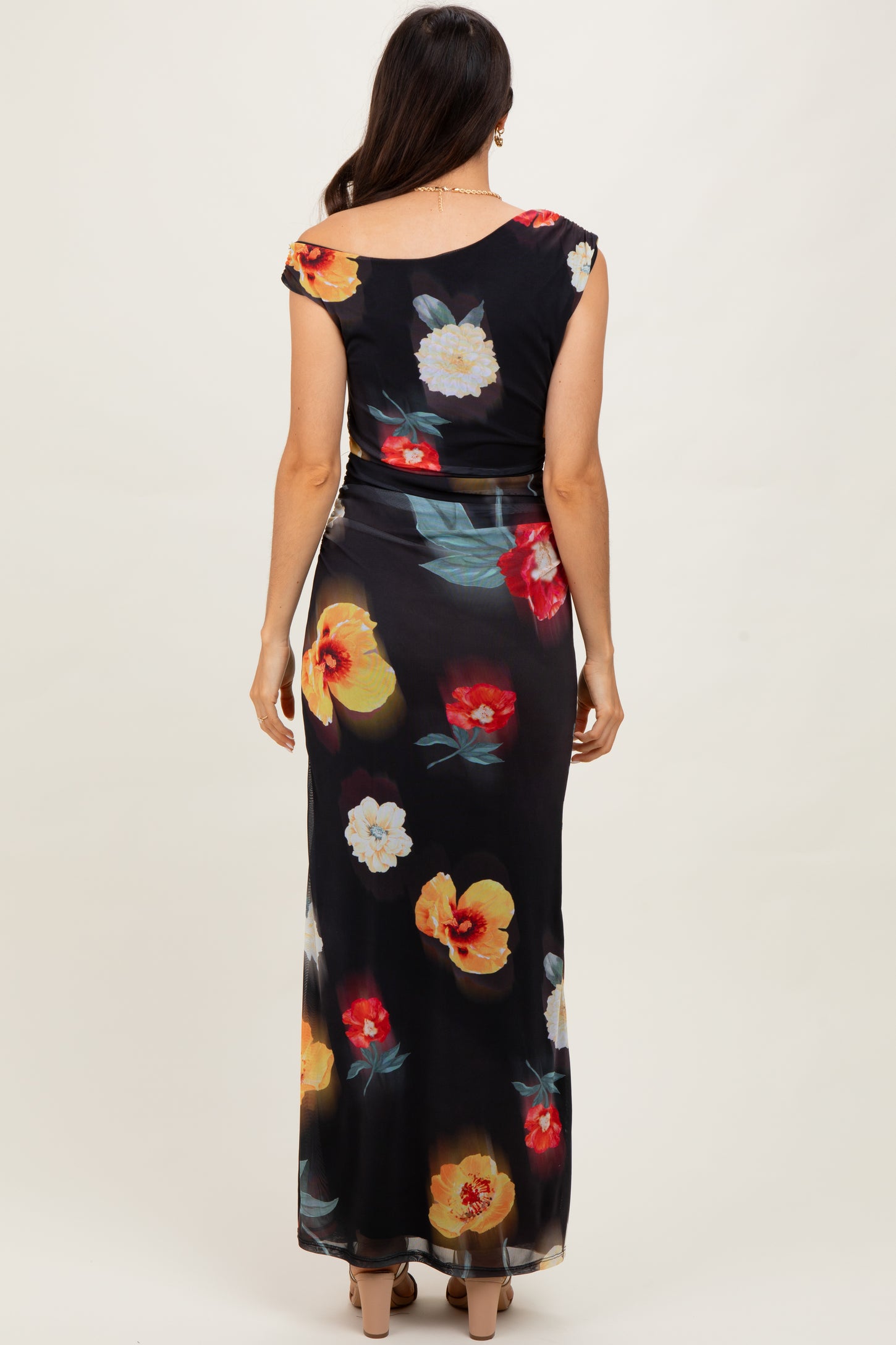 woman wearing a black floral maxi dress with a scoop back and colorful flower prints