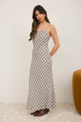woman wearing a brown and cream checkered maxi dress with thin straps and a fitted bodice