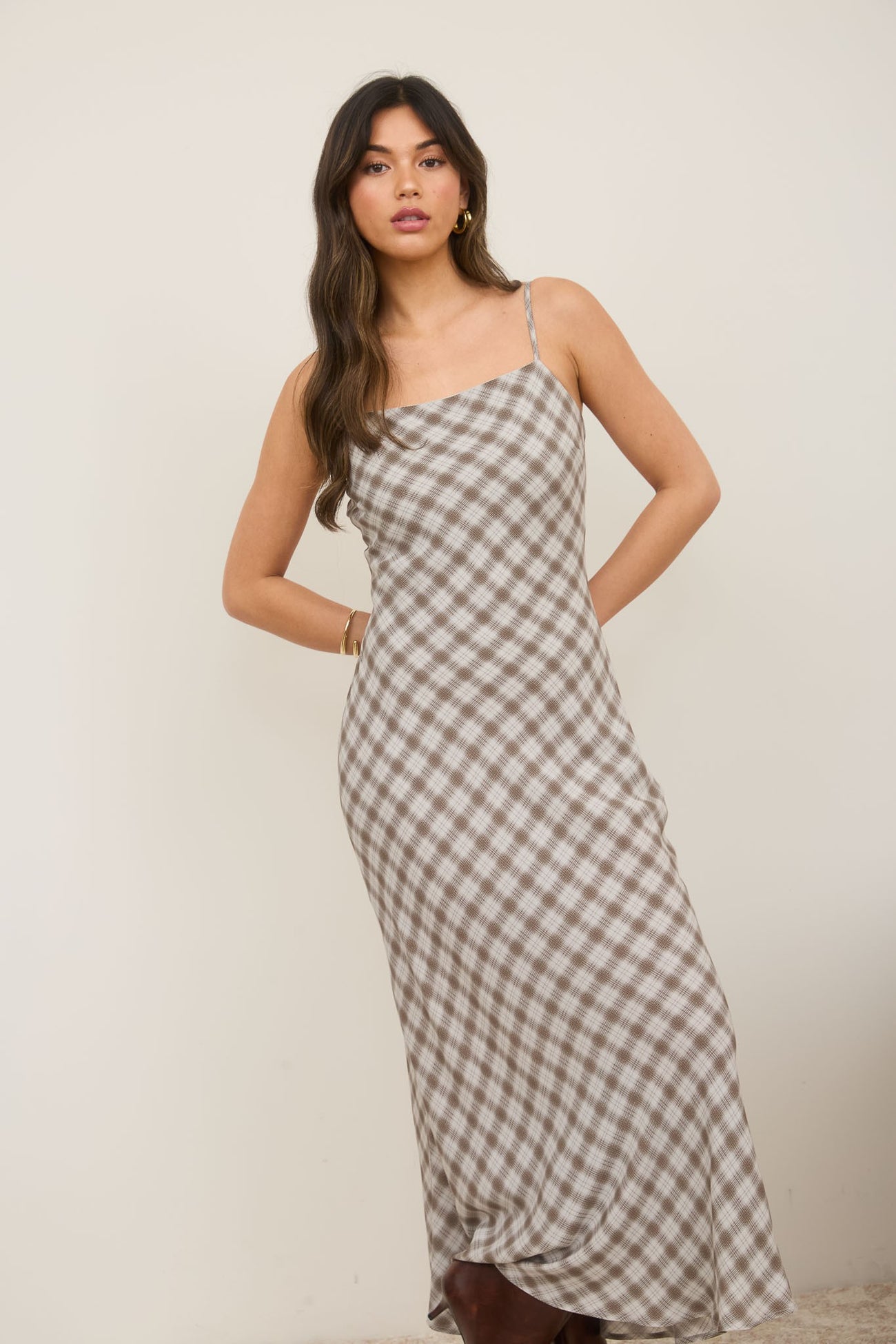 woman wearing a brown and white gingham maxi dress with adjustable spaghetti straps