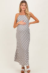 woman wearing a gray and white gingham maternity maxi dress and holding her baby bump