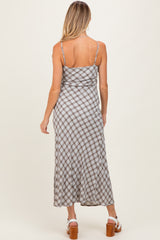 woman wearing a brown and white checkered maternity maxi dress, showing the back view and adjustable spaghetti straps