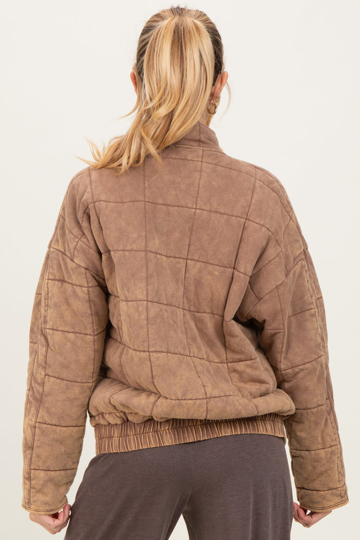 woman wearing a brown quilted maternity jacket with a relaxed fit and elastic hem, seen from the back