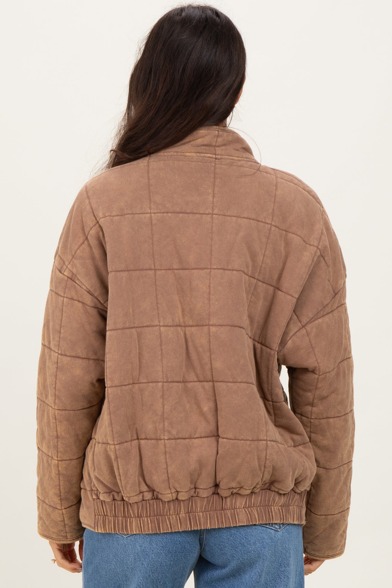 woman wearing a brown quilted jacket with a cinched waist and back view.