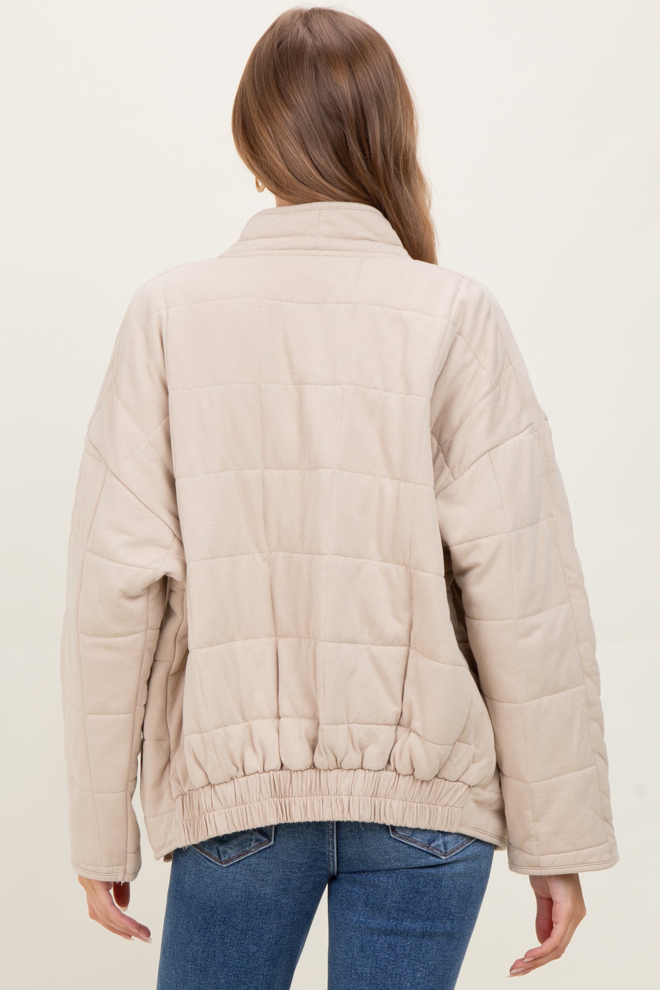 woman wearing a beige quilted maternity jacket with a cinched hem, viewed from the back
