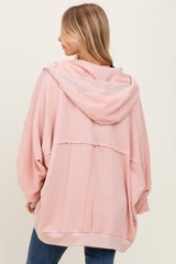woman wearing a light pink oversized hoodie with a hood and relaxed fit, showing the back view