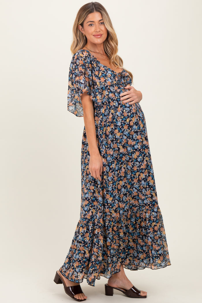 woman wearing a floral navy blue maternity maxi dress and holding her baby bump