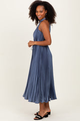 woman wearing a pleated blue maxi dress with a halter neckline and flowing silhouette
