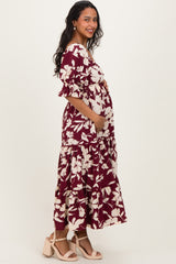 woman wearing a burgundy floral maternity maxi dress and holding her baby bump