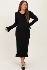 woman wearing a black maternity ribbed dress with a tie neck and ruffle hem, highlighting her baby bump