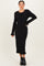 woman wearing a black ribbed midi dress with long sleeves and ruffle hem details
