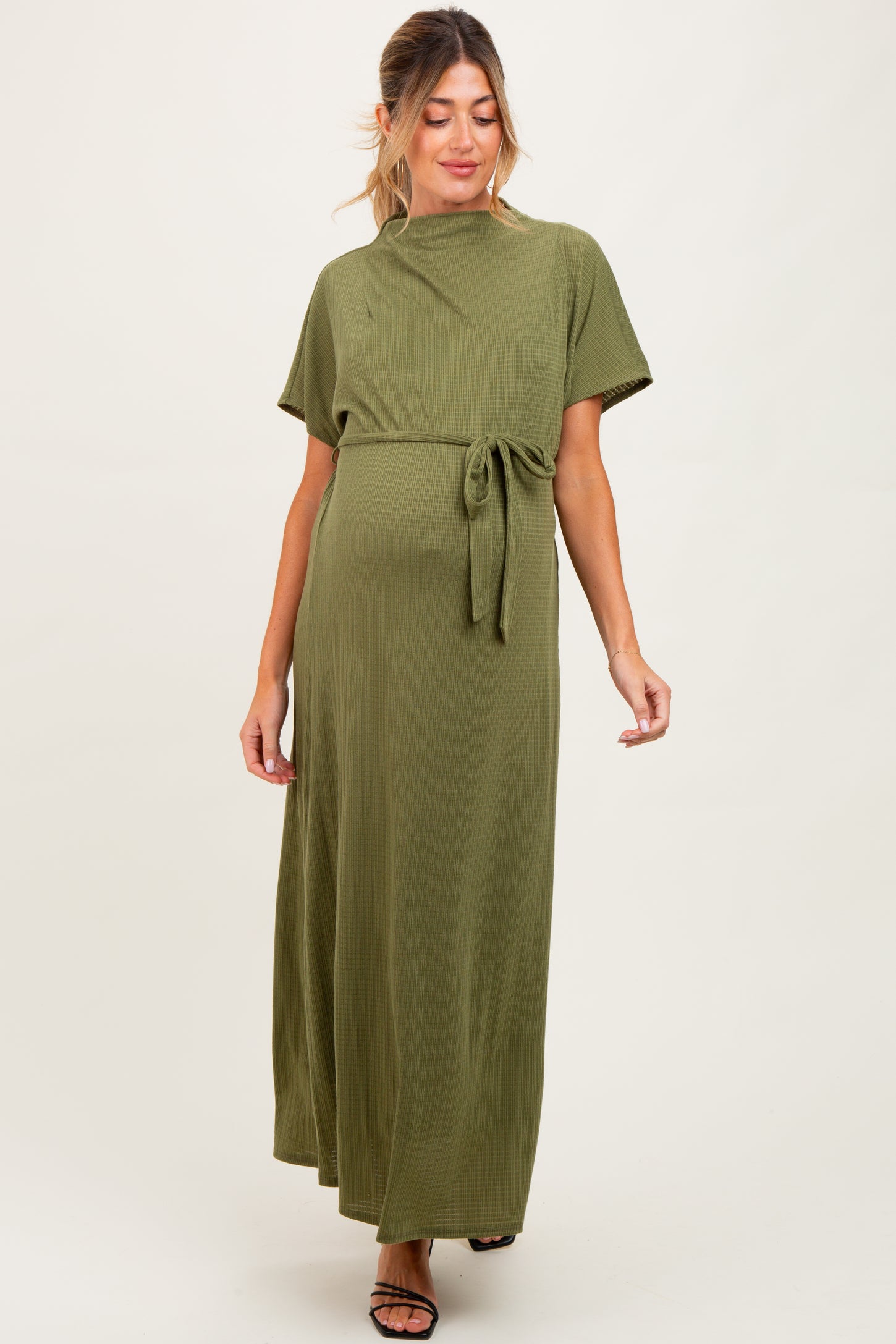 woman wearing an olive green ribbed maternity maxi dress with short sleeves and a tie at the waist, showing her baby bump