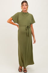 woman wearing an olive green maternity maxi dress with a tie waist and short sleeves, showing her baby bump
