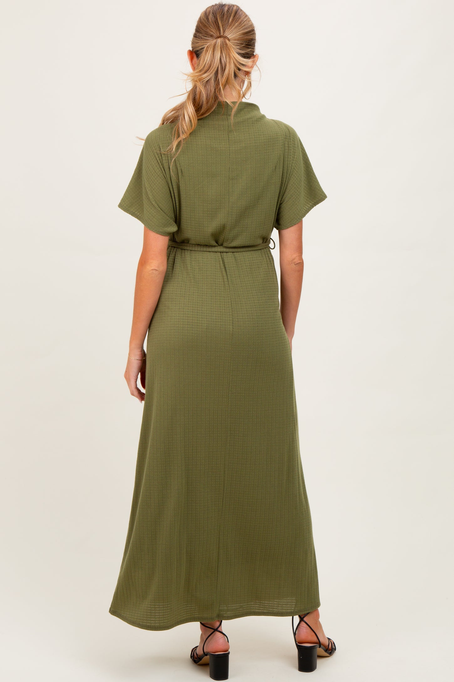 woman wearing an olive green maternity maxi dress with short sleeves and a tie waist detail.