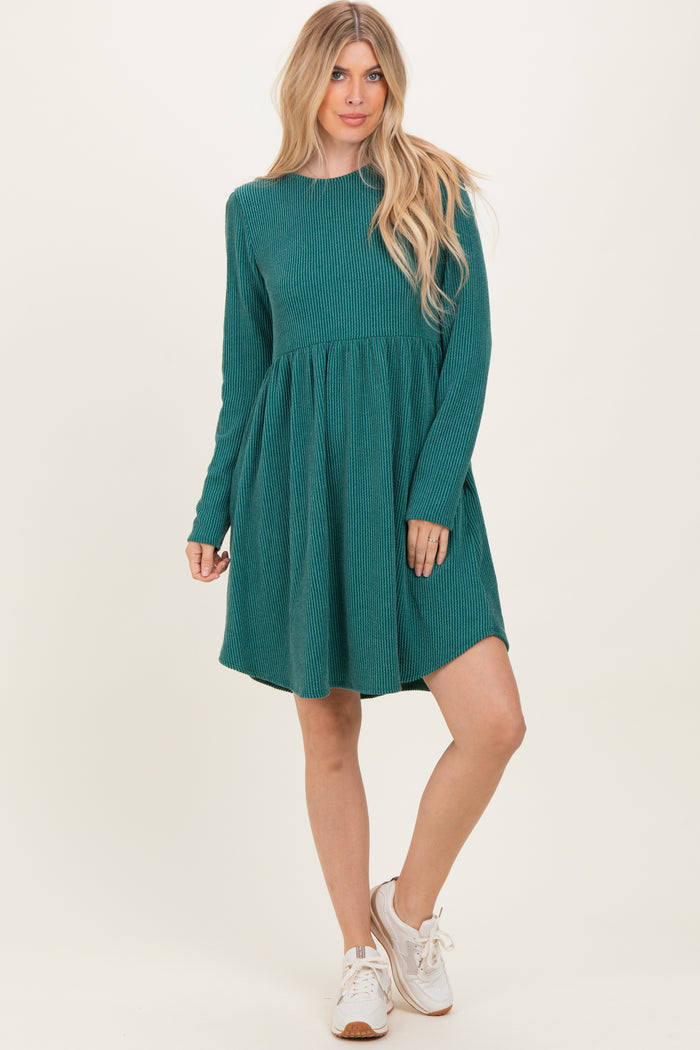 woman wearing a teal corduroy long sleeve dress with a flared skirt and white sneakers