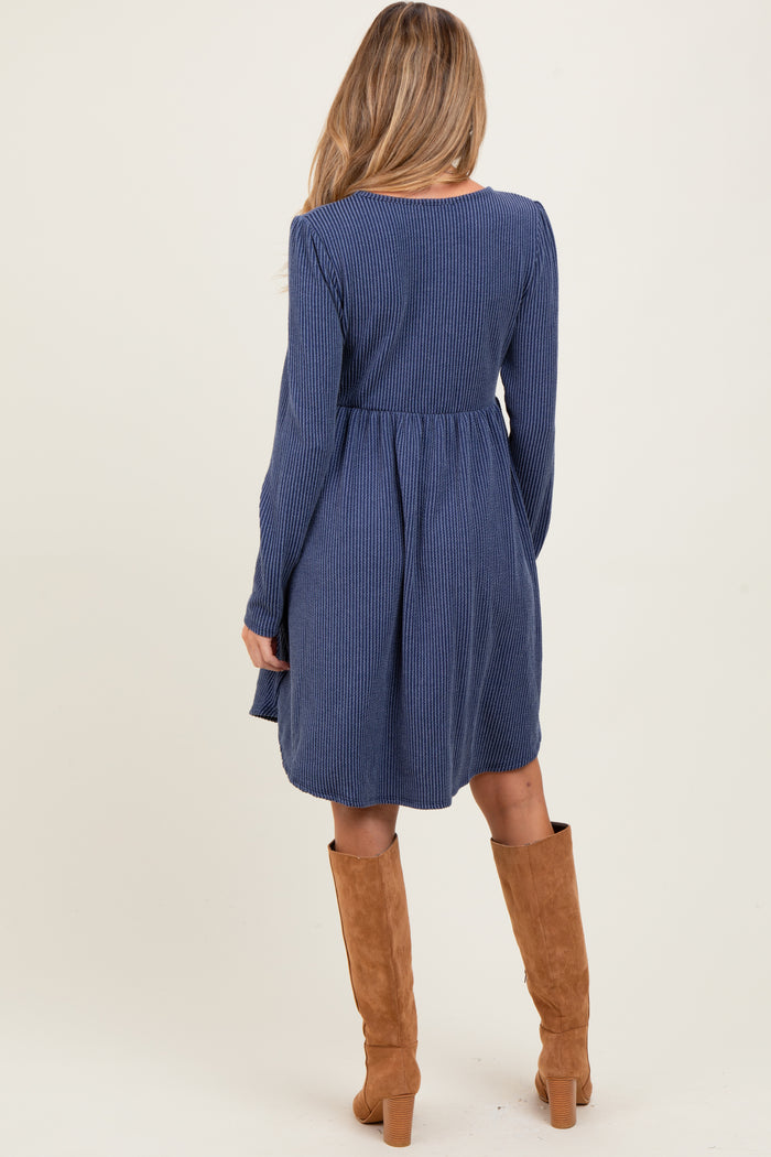 woman wearing a navy blue maternity dress with vertical stripes and long sleeves, paired with knee-high brown boots, showing her back
