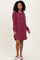 woman wearing a burgundy ribbed sweater dress with long sleeves and side slits
